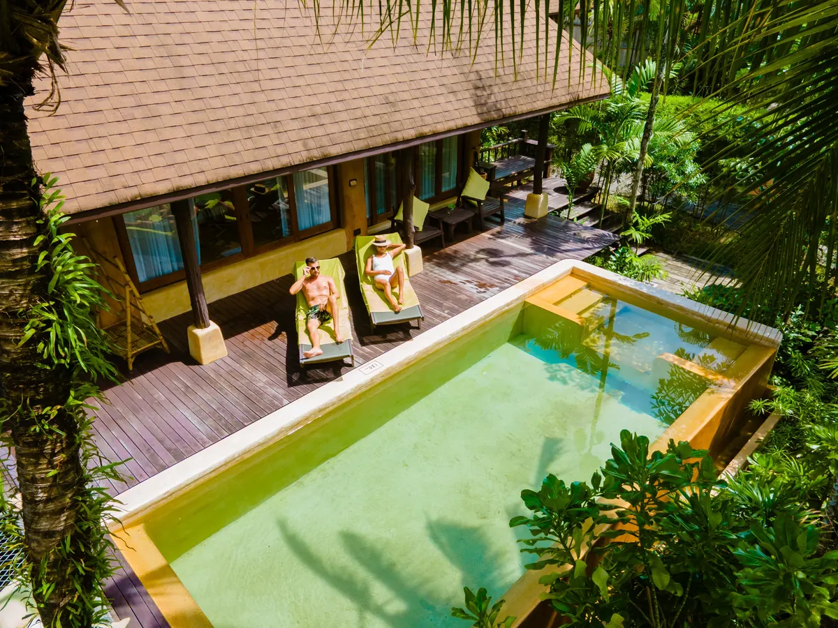 Pareja descansando junto a la piscina de una casa en Nosara, vista desde arriba